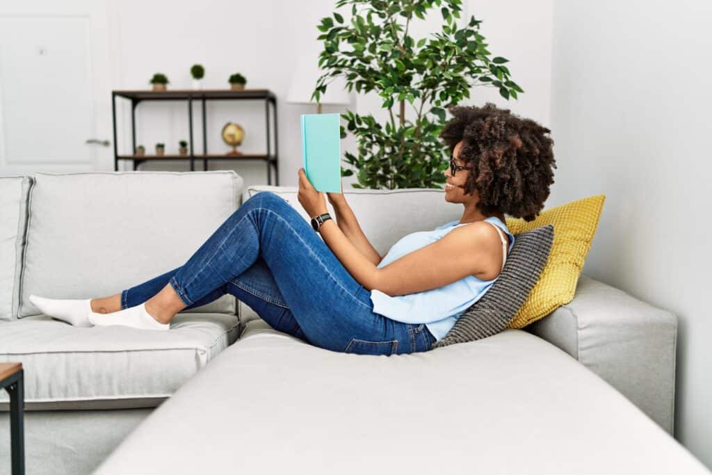 Young african american woman smiling confident reading book at home